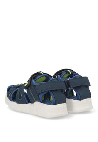 Sandalias azul marino con correas ajustables, parte superior de malla y sintético, suela blanca, detalles en verde y una plantilla texturizada para mayor agarre.