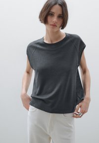 Top corto grigio scuro con maniche corte, scollatura rotonda e vestibilità comoda. Tessuto morbido con un sottile motivo a righe, abbinato a pantaloni di colore chiaro.