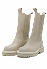 Botine de piele bej, cu un finisaj neted, panouri laterale elastice �și talpă groasă din cauciuc alb, cu margini zimțate.
