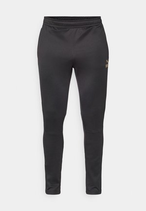 Zwarte sportieve broek gemaakt van een gladde, elastische stof. Heeft een aansluitend ontwerp met een elastische tailleband en een subtiel logo in goud.