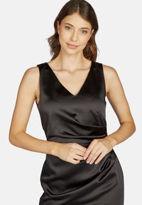 Schwarzes Satin-Kleid mit V-Ausschnitt und ärmellosem Design. Es verfügt über eine glatte Textur und eine drapierte Taille, die die Silhouette betont.