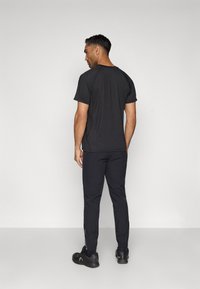 Melnas īsām piedurknēm t-krekls, pieguļošs dizains. Saskaņots ar melno šauru biksēm un melniem apaviem. Vienkārša un plūstoša izskats.