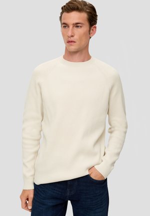 Crème kleurige geribbelde trui met een ronde hals en raglanmouwen, gecombineerd met donkere jeans, met een textuurstof en een aansluitende pasvorm.