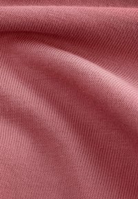 Textil med en mjuk, dämpad rosa nyans och ribbad struktur, som visar släta, jämna rader av fina linjer.
