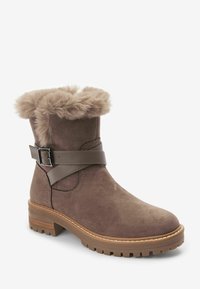 Braune Wildleder-Stiefelette mit einem Kragen aus Kunstfell, verstellbarem Riemen mit Schnalle und einer strukturierten Gummisohle. Mit abgerundeter Zehenform und Steppnähten.