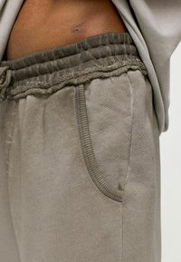 Beige sweatpants met een elastische tailleband, kantdetails en zijzakken. Getextureerde stof met een licht versleten uitstraling.