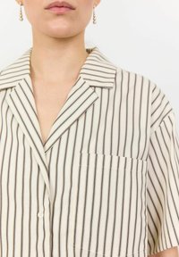 Short-sleeve, light fabric shirt with vertical beige and dark brown stripes, featuring a notched collar and a left chest pocket.