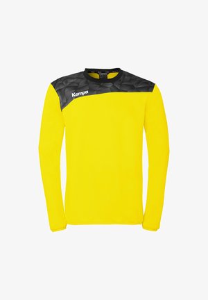 Gelbes langärmeliges Sporttrikot mit einem schwarzen geometrischen Muster über den Schultern und dem weißen "Kempa"-Logo auf der oberen Brust.