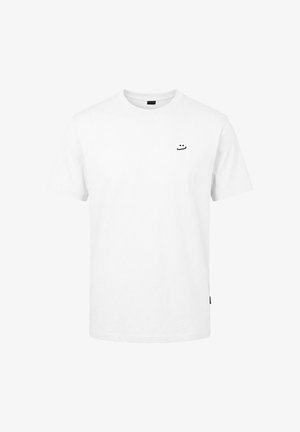 T-shirt blanc à manches courtes avec col rond, orné d'un petit smiley minimaliste noir brodé sur le haut gauche de la poitrine.
