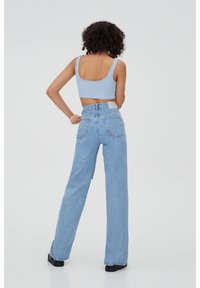 Top corto a coste blu chiaro e jeans in denim blu chiaro a vita alta con gamba dritta e zip frontale, dotati di tasche posteriori e una fascia in vita.