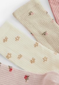 Ponožky po kolená v krémovej, béžovej a ružovej farbe. Textúrované rebrovanie s kvetinovými vzormi v rôznych odtieňoch. Mäkká tkanina s jemnými detailmi.