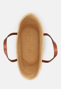 Gevlochten strooien mand met een gladde, ovale vorm, voorzien van bruine leren handvatten. Het interieur heeft concentrische lijnpatronen, lichtgewicht en flexibel.