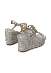 Sandalias de cuña plateadas con plataforma de yute trenzado, acentos decorativos de strass y finas correas de tobillo ajustables. Acabado metálico suave.