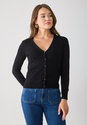 Zwarte v-hals cardigan met lange mouwen, zes knopen aan de voorkant en een getailleerde pasvorm, gecombineerd met denim jeans, tentoongesteld tegen een neutrale achtergrond.