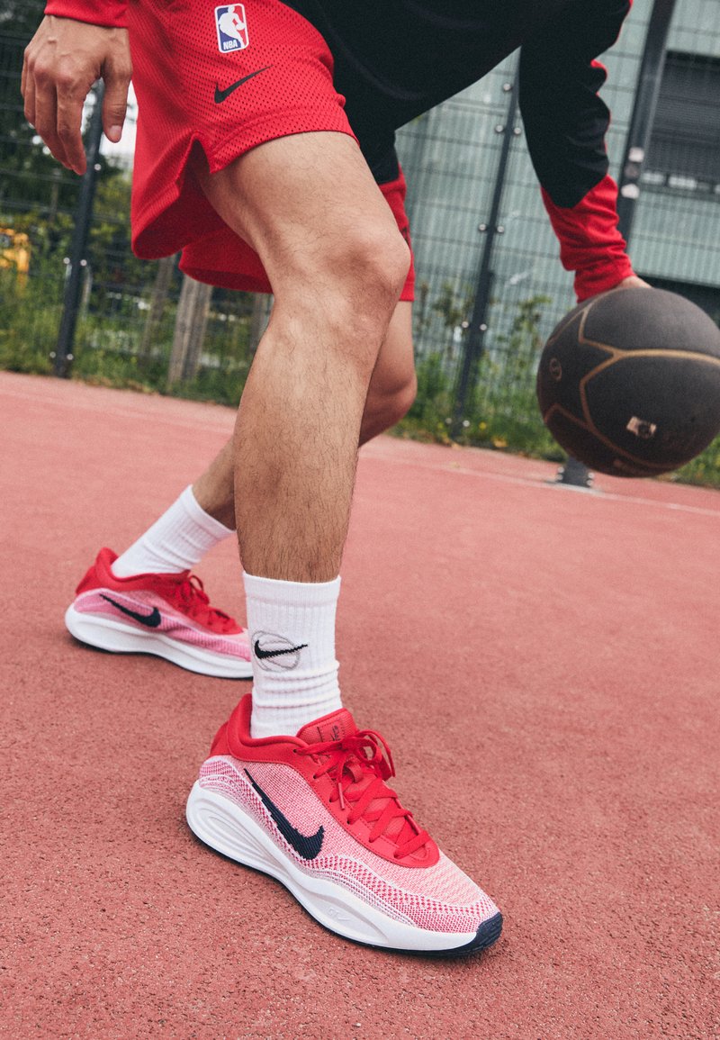 Czerwone, lekkie buty do koszykówki z siateczkowym wzorem i kontrastującymi granatowymi akcentami, zestawione z białymi skarpetkami z czarnym logo.