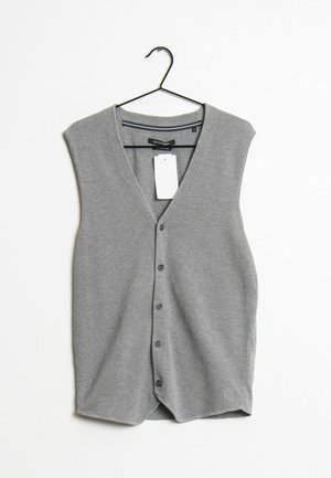 Chaleco de punto gris con escote en V, diseño sin mangas, seis botones delanteros y una etiqueta colgante. Tejido texturizado.