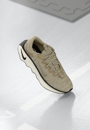 Beige atletiske sko med tekstureret overdel af stof, akcentueret af en sort sål og et glat, kurvet design. Snøre lukning med brandingdetaljer.