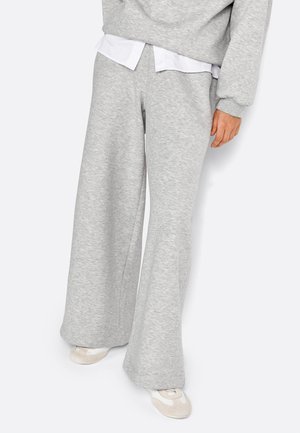 Pantalons de survêtement gris à jambes larges en tissu doux, dotés d'un design fuselé, d'une taille élastique et associés à une chemise blanche à col en dessous.