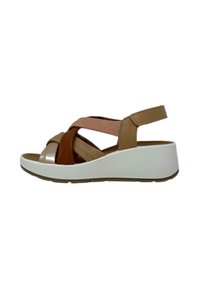 Sandalo con zeppa e design a cinghie incrociate nei colori marrone, beige e con dettagli metallici; presenta una suola piattaforma bianca e un cinturino alla caviglia regolabile.