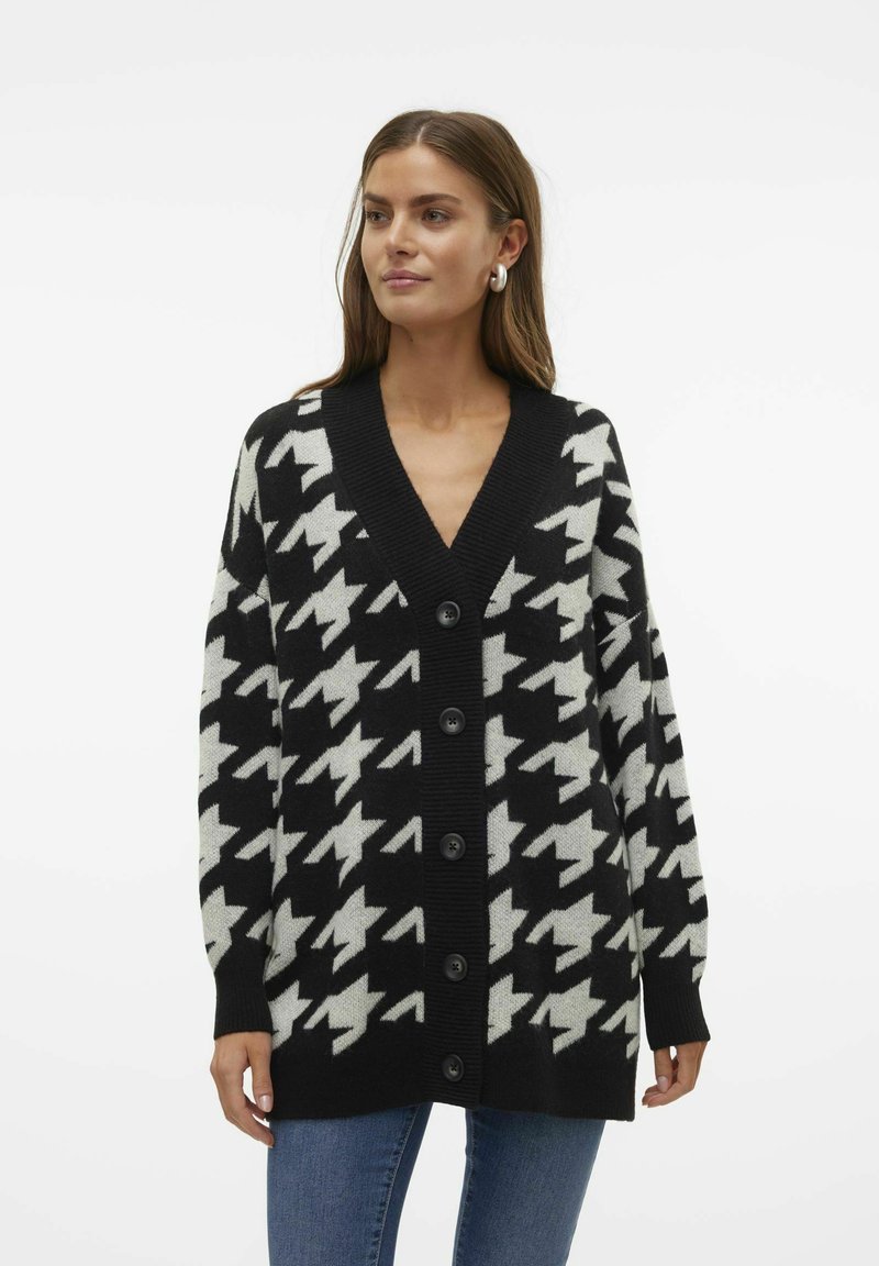 Svart och vit houndstooth-mönstrad cardigan med V-ringning, oversize passform och fem svarta knappar fram. Stickad tyg.