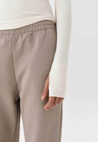 Lange mouw geribbelde top in gebroken wit, gecombineerd met zachte beige sweatpants met een elastische tailleband en een ontspannen pasvorm, die een gladde textuur laten zien.