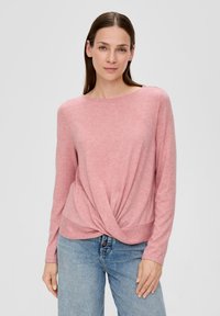 Helles rosa Langarmshirt mit gedrehtem Vorderdesign, Rundhals-Ausschnitt, weicher Textur, kombiniert mit blauen Denim-Jeans.