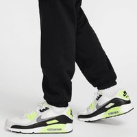 Zapatillas blancas y negras con acentos en amarillo neón, que cuentan con una parte superior texturizada, líneas de diseño únicas y amortiguación de aire visible.