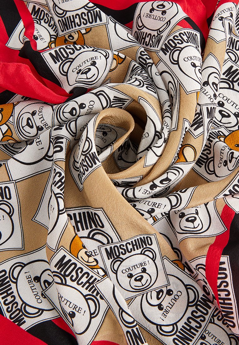 Seidenschal mit beigem Hintergrund, der sich wiederholende Bärenmotive und den Text "MOSCHINO COUTURE!" in Schwarz und Braun zeigt, umrandet von roten Akzenten.