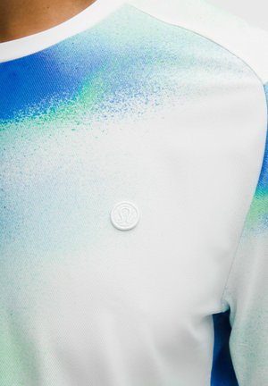 Lühikeste varrukatega valge sportlik särk sinise ja rohelise laineliste laikudega, millel vasakul rinnal on ümmargune logo. Tekstureeritud kangas.