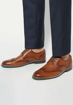 Brown leather dress shoes with a smooth finish, perforated detailing, and a classic lace-up design. Rubber soles and contrasting blue accents.