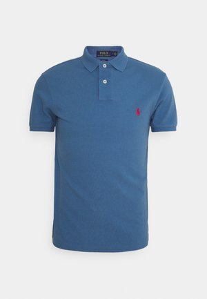 Polo bleu à manches courtes avec deux boutons blancs, col et logo Ralph Lauren rouge brodé sur la poitrine gauche.
