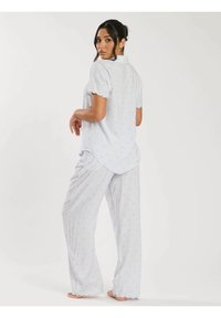 Ljusblå pyjamas med kort ärm och vågiga kanter. Mjuk tyg med ett diskret prickigt mönster och avslappnad passform.