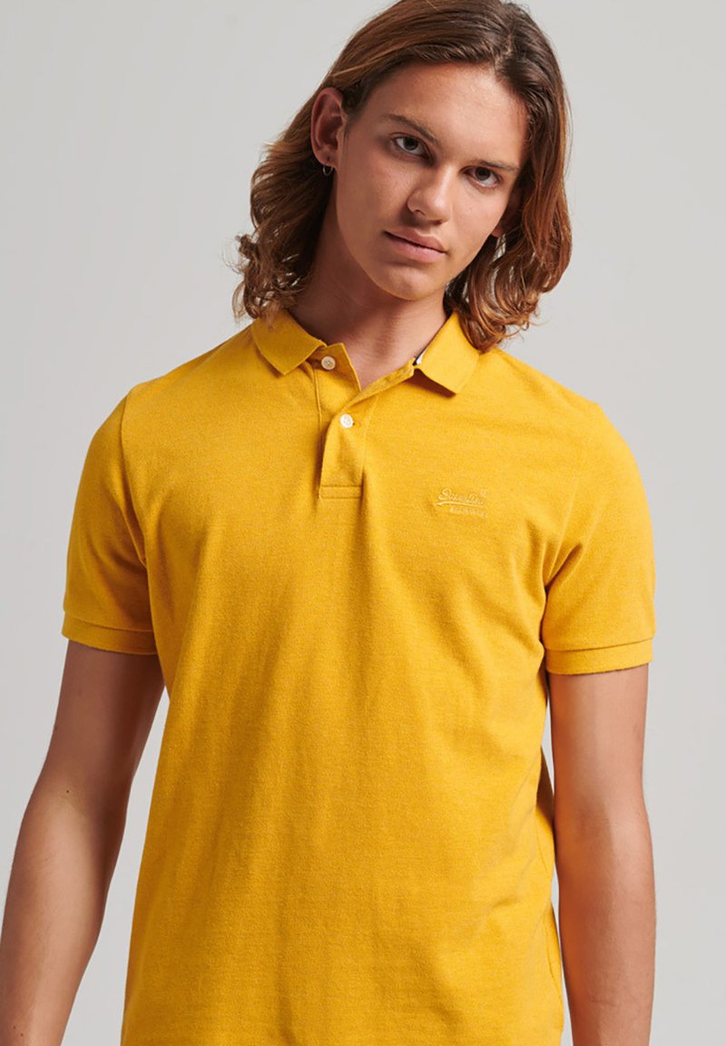 Gul polo t-shirt med klassisk krave, korte ærmer og et diskret logo på brystet. Fremstillet af struktureret bomuldsmateriale.