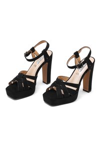 Sandali con tacco alto in suede nero, design a strisce incrociate, punta quadrata e cinturino alla caviglia. Tacco spesso e soletta imbottita per comfort.