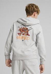 Siva hoodie s kapuljačom s živopisnom grafikom na leđima koja prikazuje šarene likove i tekst "UJEDINJENI." Mekan materijal, ležeran kroj.