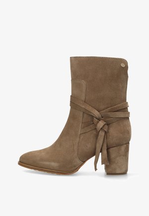 Braune Wildleder-Ankle-Boots mit spitzem Zehenbereich, gewickeltem Banddetail und blockigem Absatz. Sie verfügen über eine glatte Textur und ein minimalistisches Design.