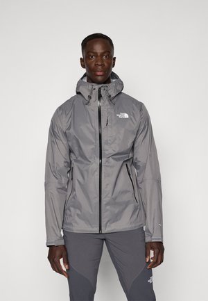 Veste imperméable grise avec capuche, fermeture éclair à l'avant, cordons de serrage ajustables et poches latérales. Logo visible sur la poitrine gauche.