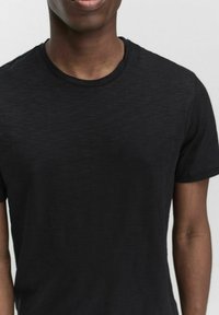 Sort kortærmet t-shirt lavet af et blødt, let stof med rund halsudskæring, der viser en subtil tekstureret finish.