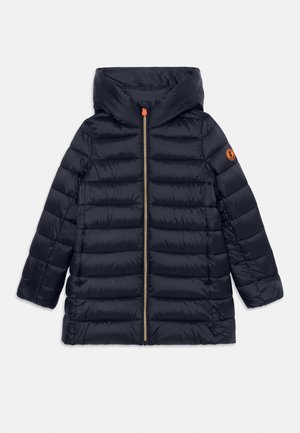 Abrigo acolchado tipo puffer en azul marino con cuello alto, cierre frontal con tirador naranja, bolsillos laterales y parche de logo naranja en la manga izquierda.