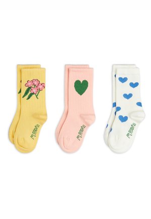 Three pairs of folded socks: yellow with pink flowers, light pink with green heart, and white with blue hearts, each with "M. ROOM" text.