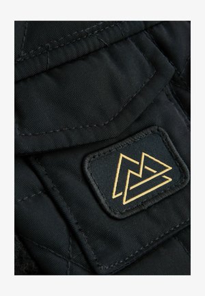 Fekete steppelt anyag, amelynek texturált felülete van. Arany logó pecséttel díszített, geometrikus mintázattal, amely egy hajtókán helyezkedik el.