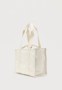 Sac fourre-tout blanc en matière lisse, doté de longues anses en tissu avec logo. Forme rectangulaire avec côtés structurés et détails minimaux.