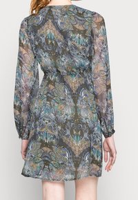 Průhledné šaty se vzorem a stáhnutým pasem. Mají dlouhé rukávy a vícebarevný design v modrých, zelených a zemitých tónech.