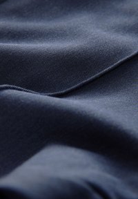 Tela de un oscuro azul marino con una textura suave, que presenta patrones de tejido diagonal y pliegues doblados, creando profundidad e interés visual.