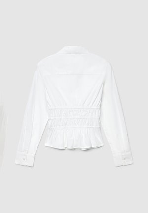Chemise blanche à manches longues avec taille froncée, col et poignets boutonnés. Ourlet légèrement péplum et texture de tissu en coton lisse.