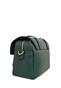 Borsa in pelle verde con forma strutturata, cerniera color oro, manici per il trasporto e dettagli di cuciture sottili. Texture liscia con linee pulite.