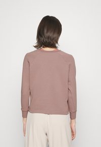 Felpa in cotone marrone con collo rotondo, maniche lunghe e colletto interno a contrasto. Presenta una vestibilità comoda e polsini a coste.