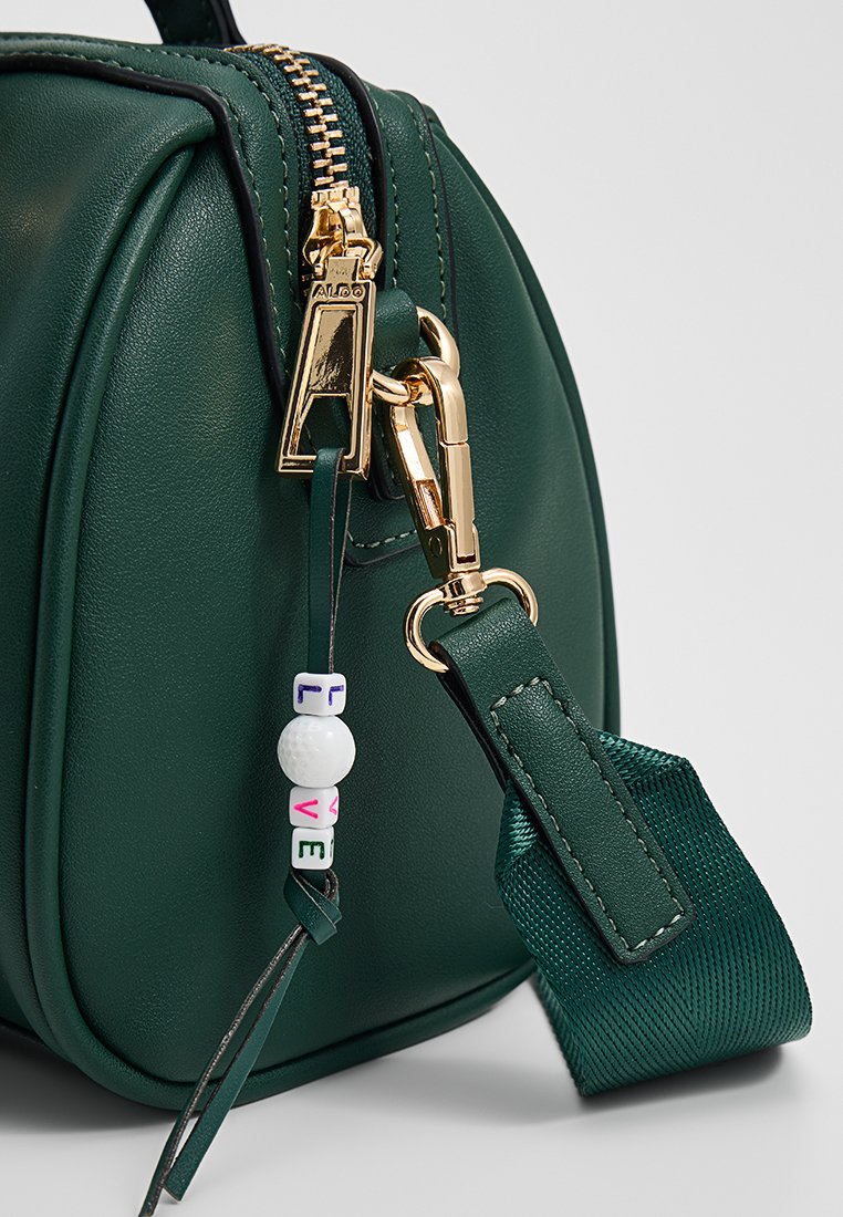 Borsa a mano in pelle verde con forma arrotondata, hardware dorato e un dettaglio decorativo a forma di perla "LOVE" su una tracolla. Presenta una tracolla testurizzata.
