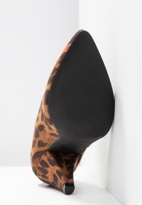 Leopardenmuster High-Heel-Schuh mit einem strukturierten Wildlederobermaterial, spitzem Zeh und einer schwarzen Gummisohle, im Winkel auf einem weißen Hintergrund präsentiert.