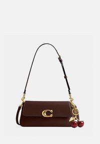 Sac à main en cuir marron foncé avec fermoir doré "C" et breloque en forme de cerise dorée et rouge suspendue sur le côté, muni d'une bandoulière ajustable.